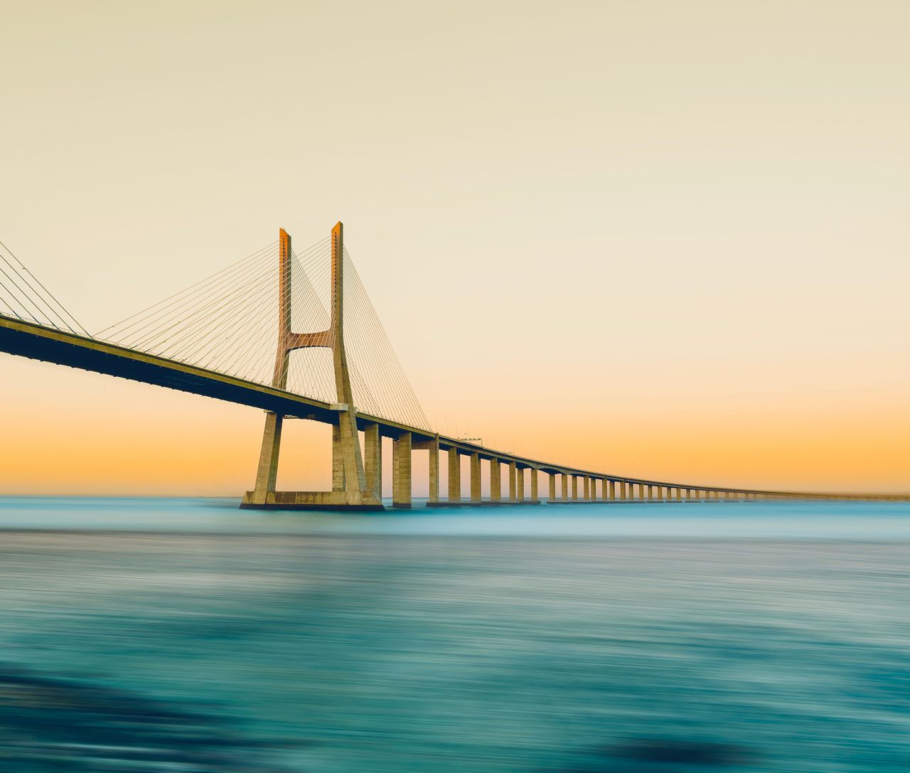 A serene view of the Vasco da Gama Bridge in Lisbon with a stunning sunset backdrop.